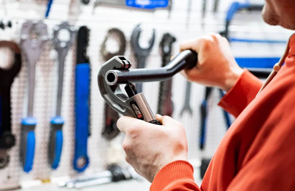 Plumber holding a pipe wrench in front of a tool wall